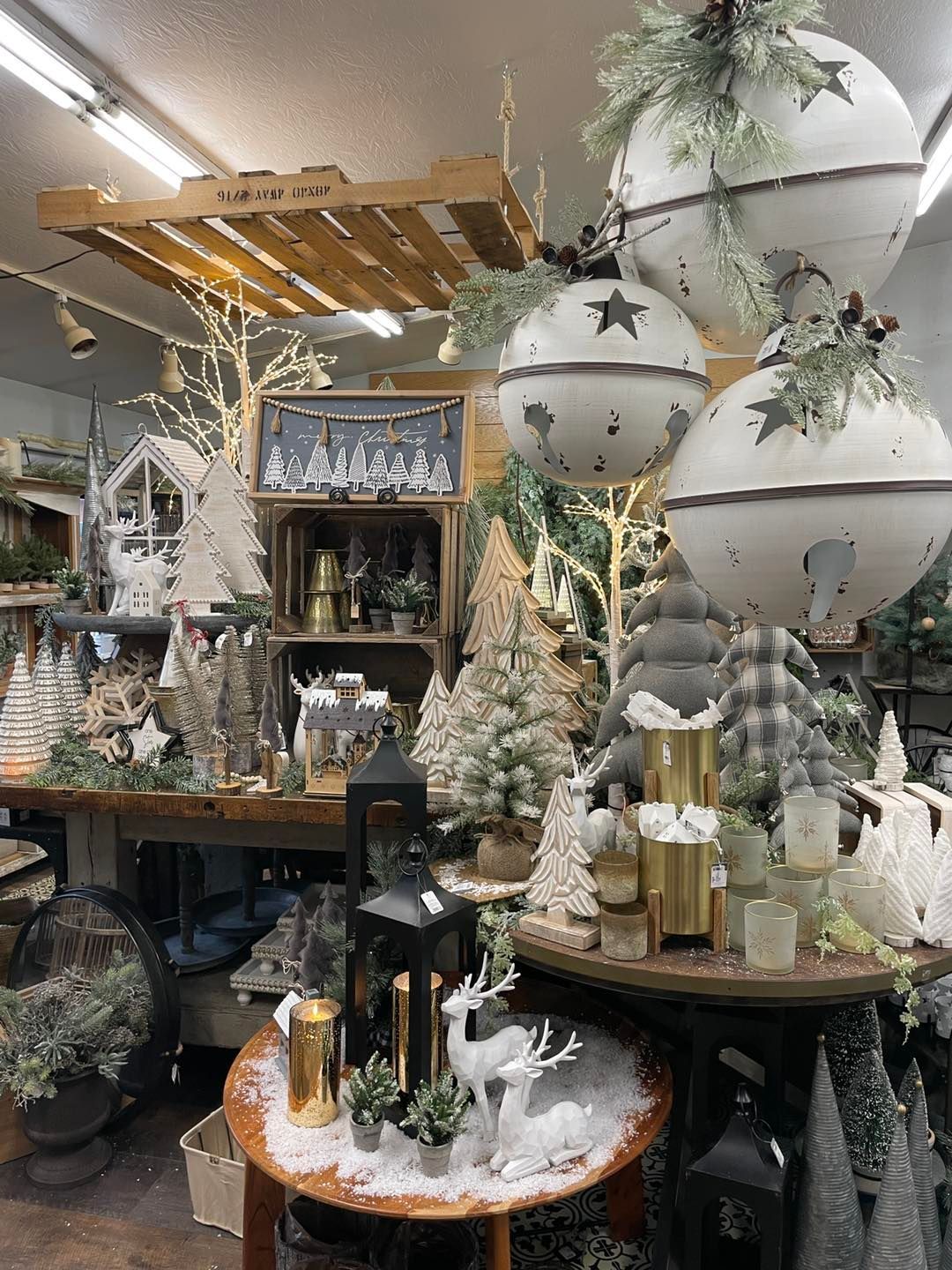 Christmas decor display with snow-covered reindeer, ornaments, and lanterns in a shop.