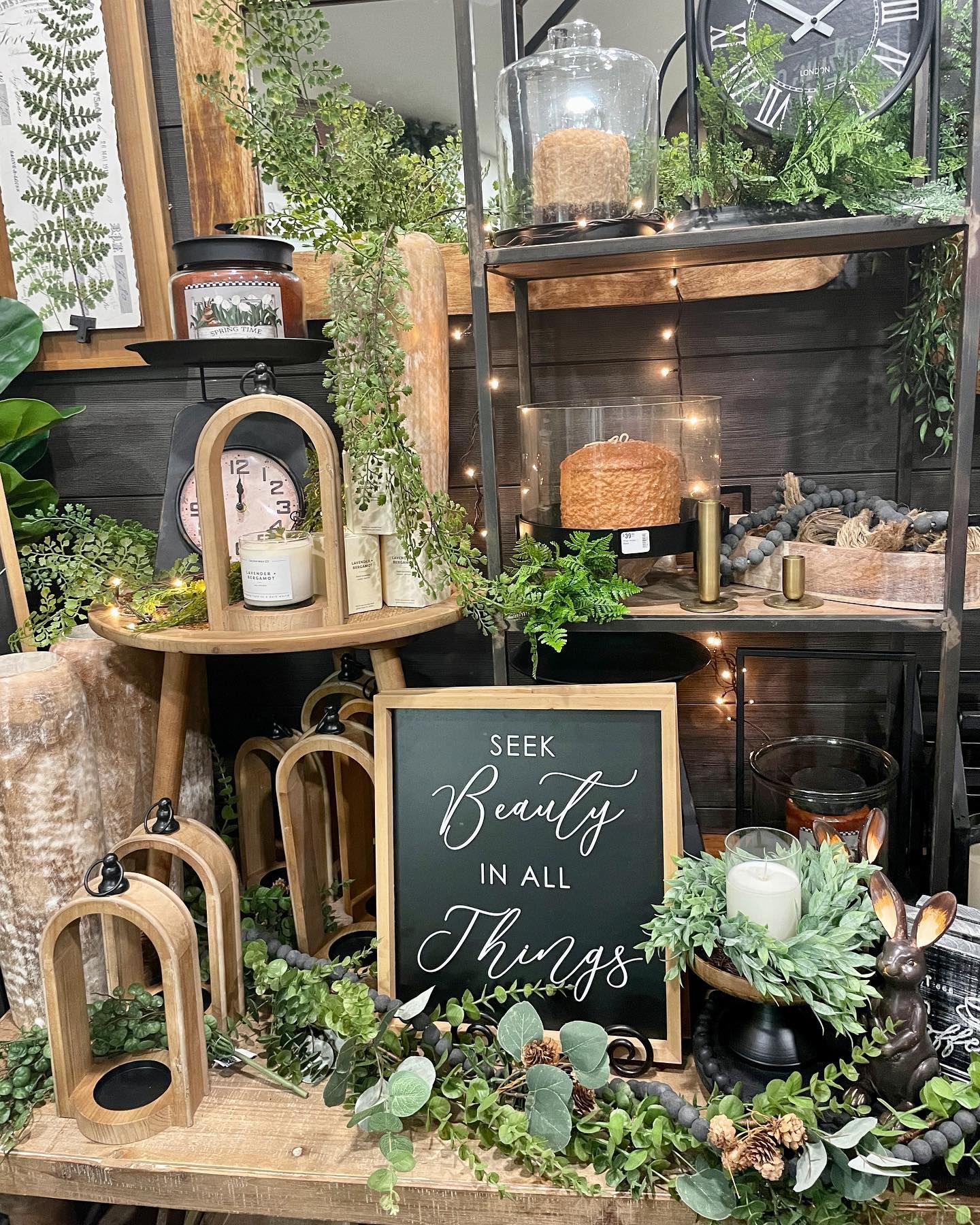 Display with plants, lanterns, shelves, and chalkboard sign saying 