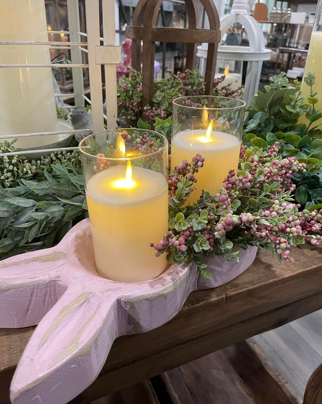 Pink bunny-shaped candle holder with lit pillar candles and floral accents on a wooden table.