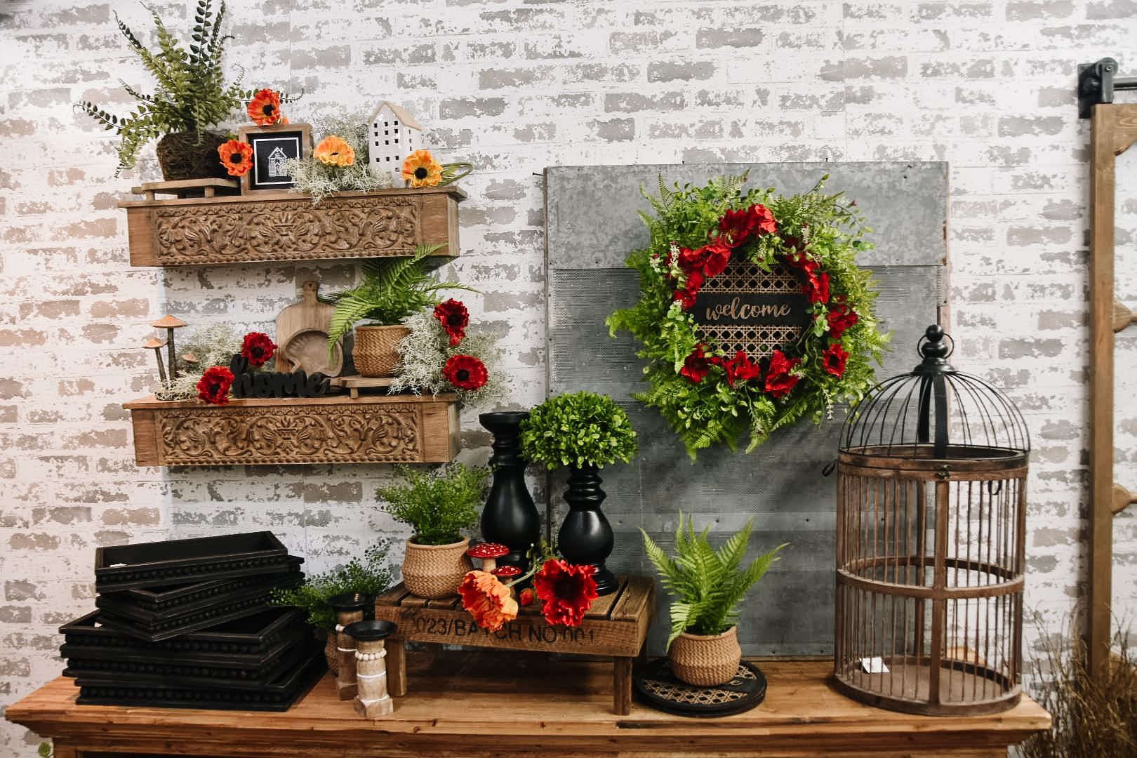 Wooden table with floral arrangements and decorative items against a brick wall.