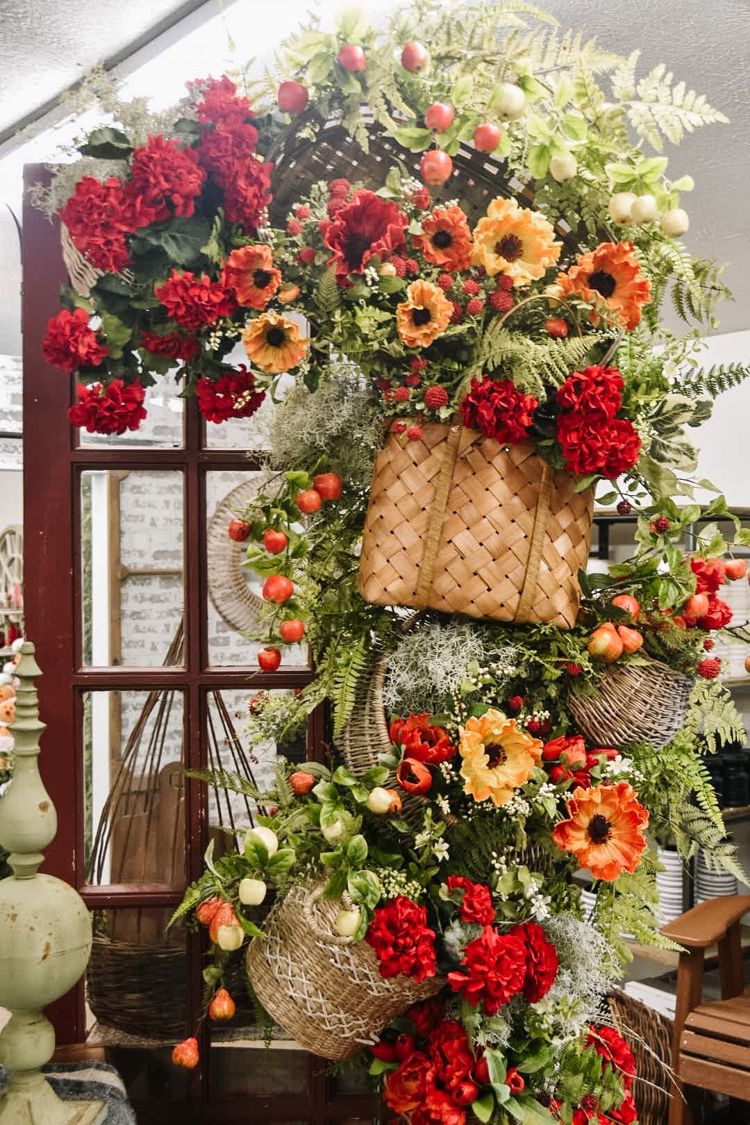 An elaborate floral arrangement with red and orange flowers on a red-framed window.