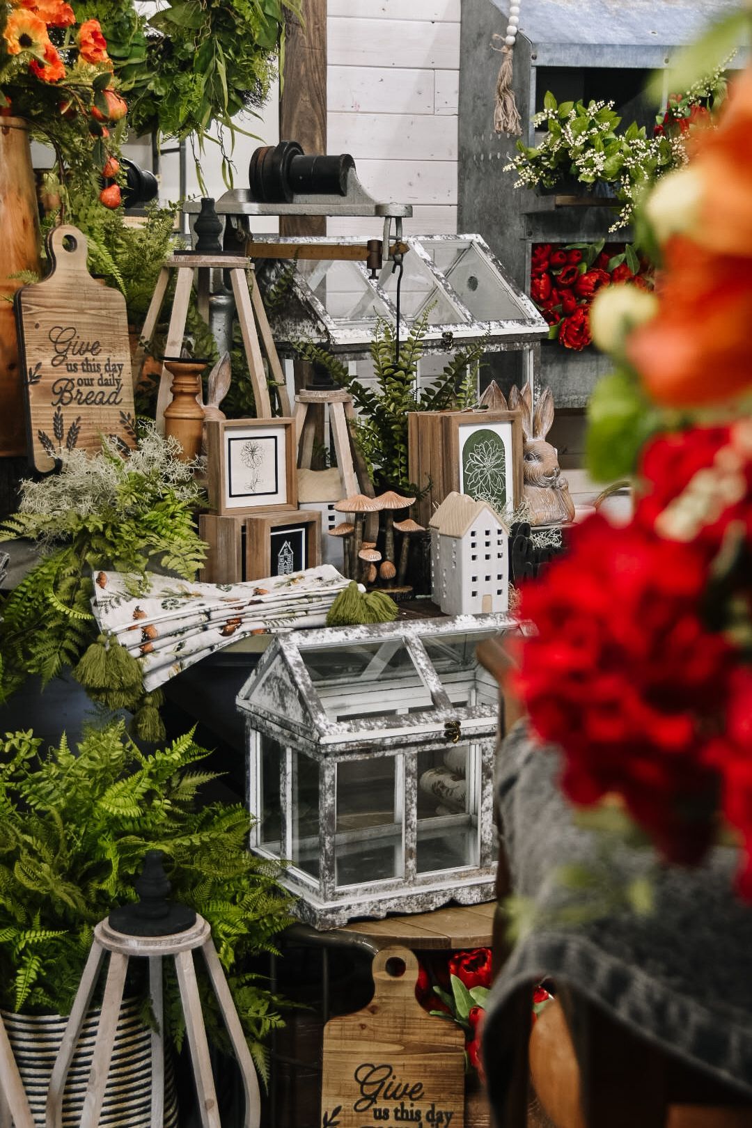 Display of decorative objects: small greenhouses, wooden cutting boards, and plants.