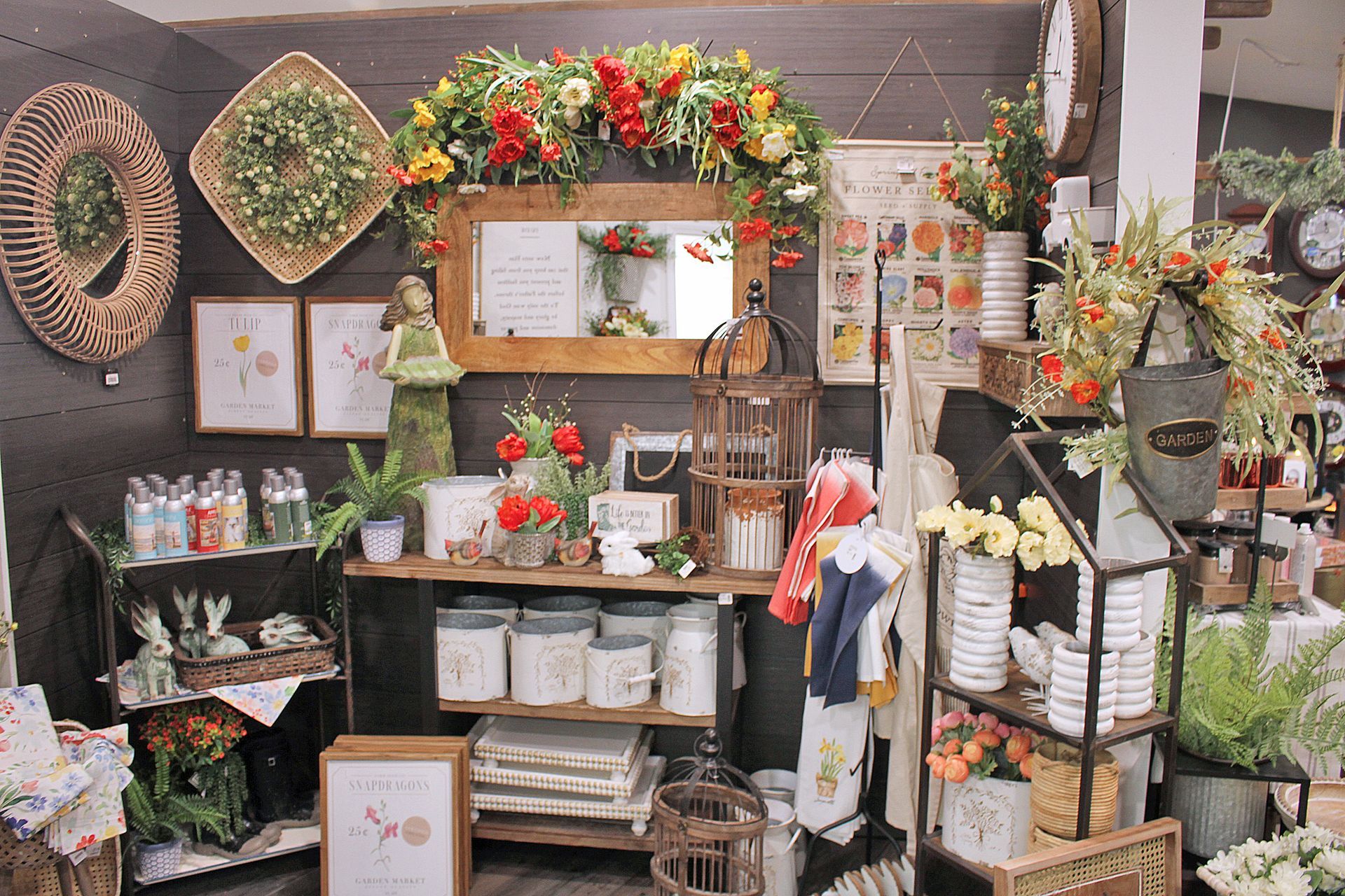 Display of home decor items, including floral arrangements, mirrors, and vintage-style accents.