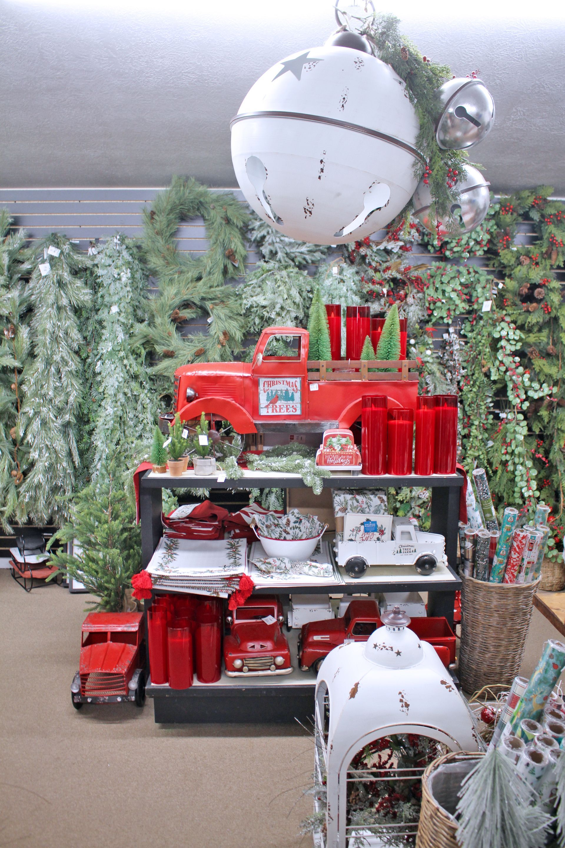 Christmas decor display with red trucks, trees, and wreaths.