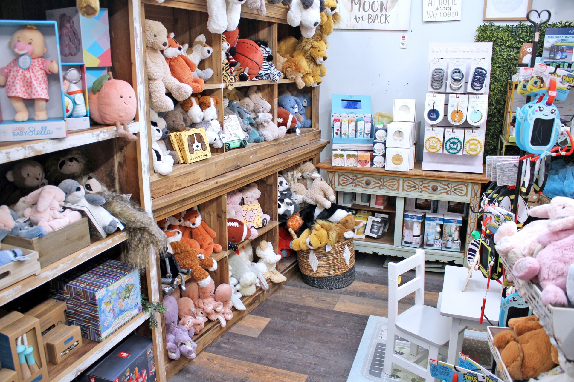 Interior of a retail shop filled with stuffed animals, dolls, and children's toys on wooden shelves.