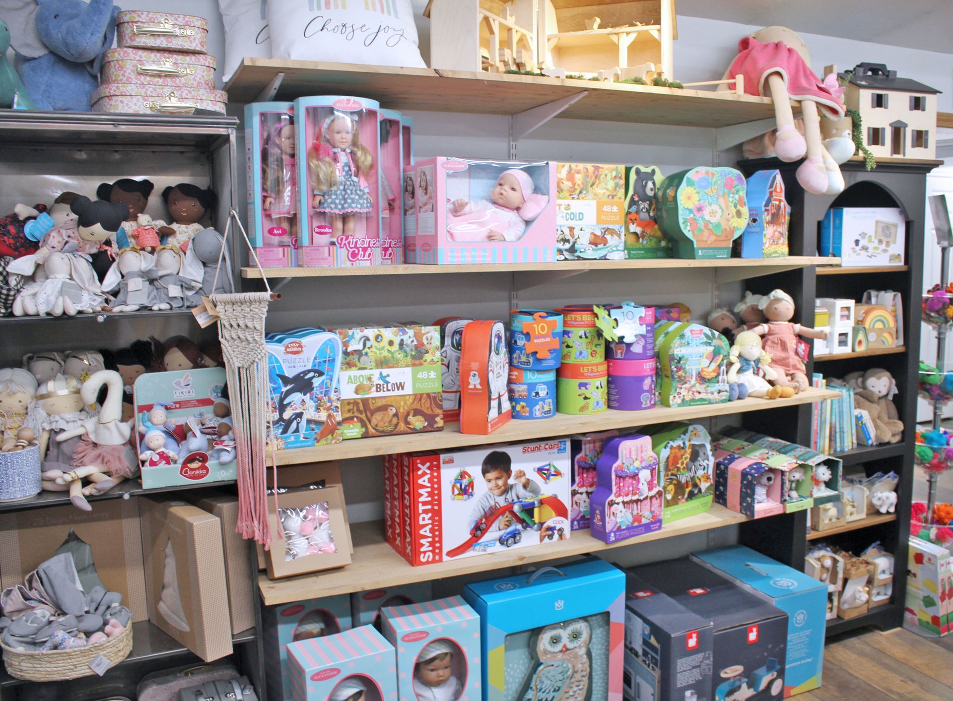 Shelves stocked with toys in a store; dolls, puzzles, stuffed animals, and other children's items.