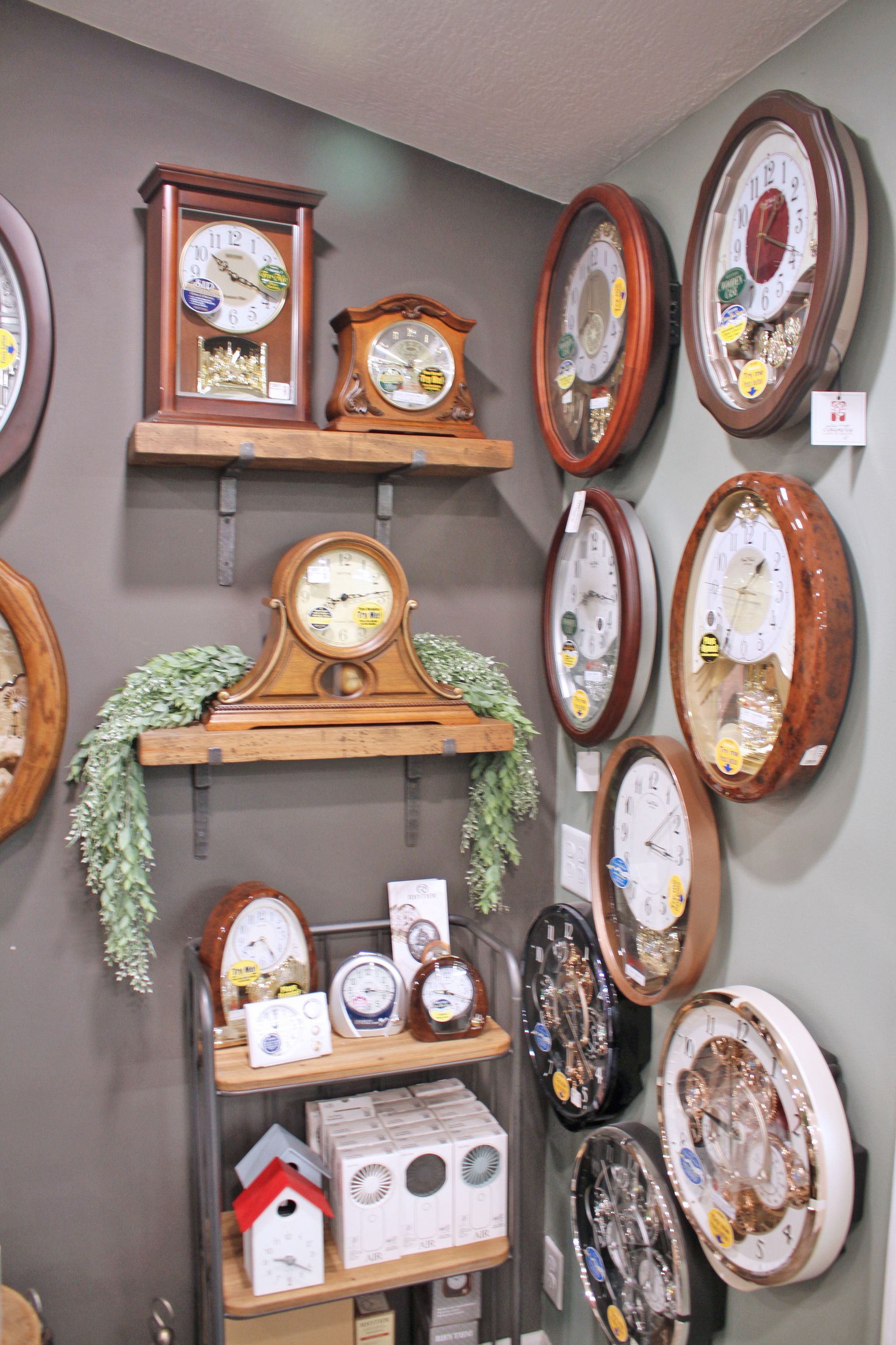 Clocks displayed on shelves and walls; various shapes, sizes, and wooden frames.