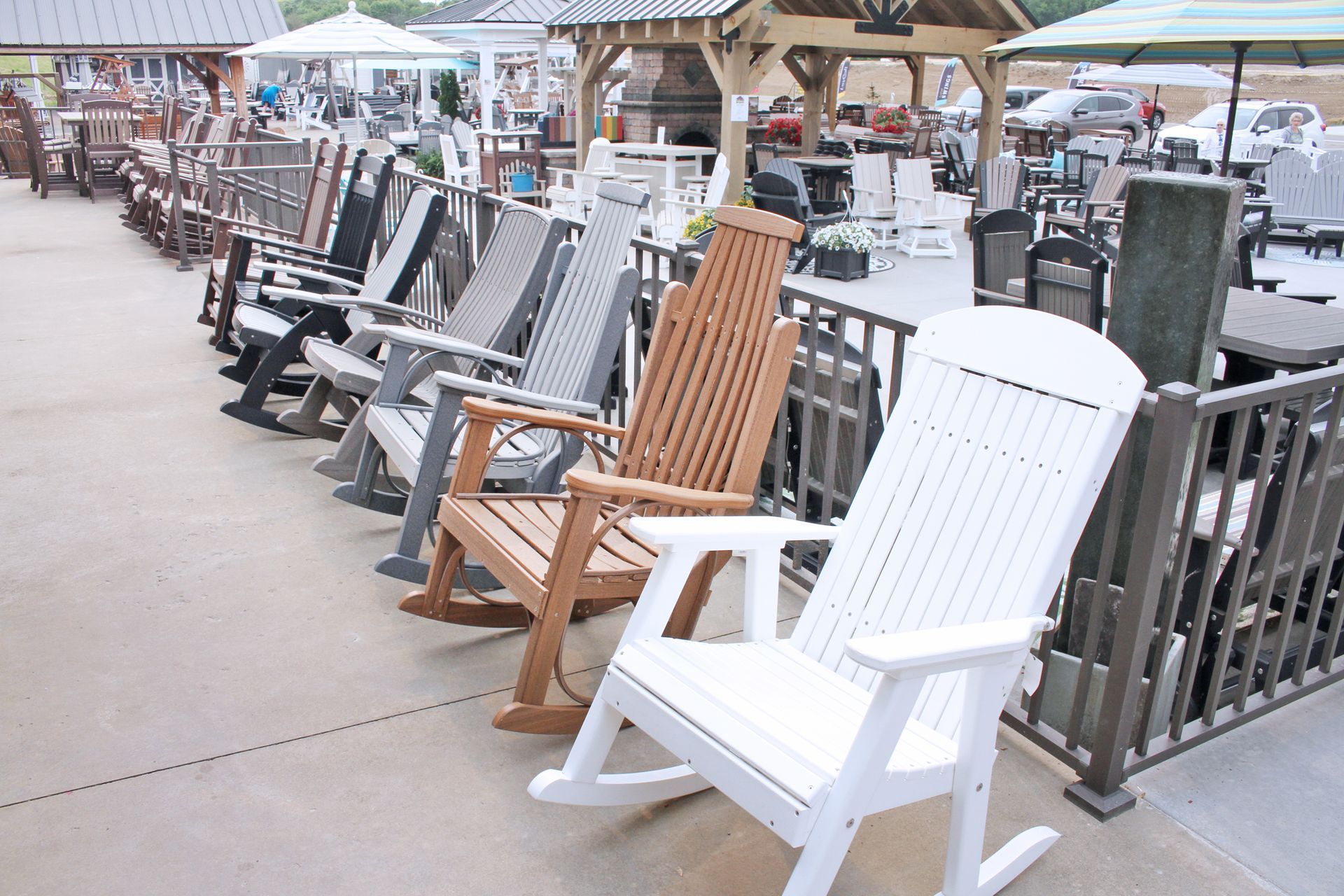 Outdoor furniture display: rows of colorful Adirondack rocking chairs for sale.