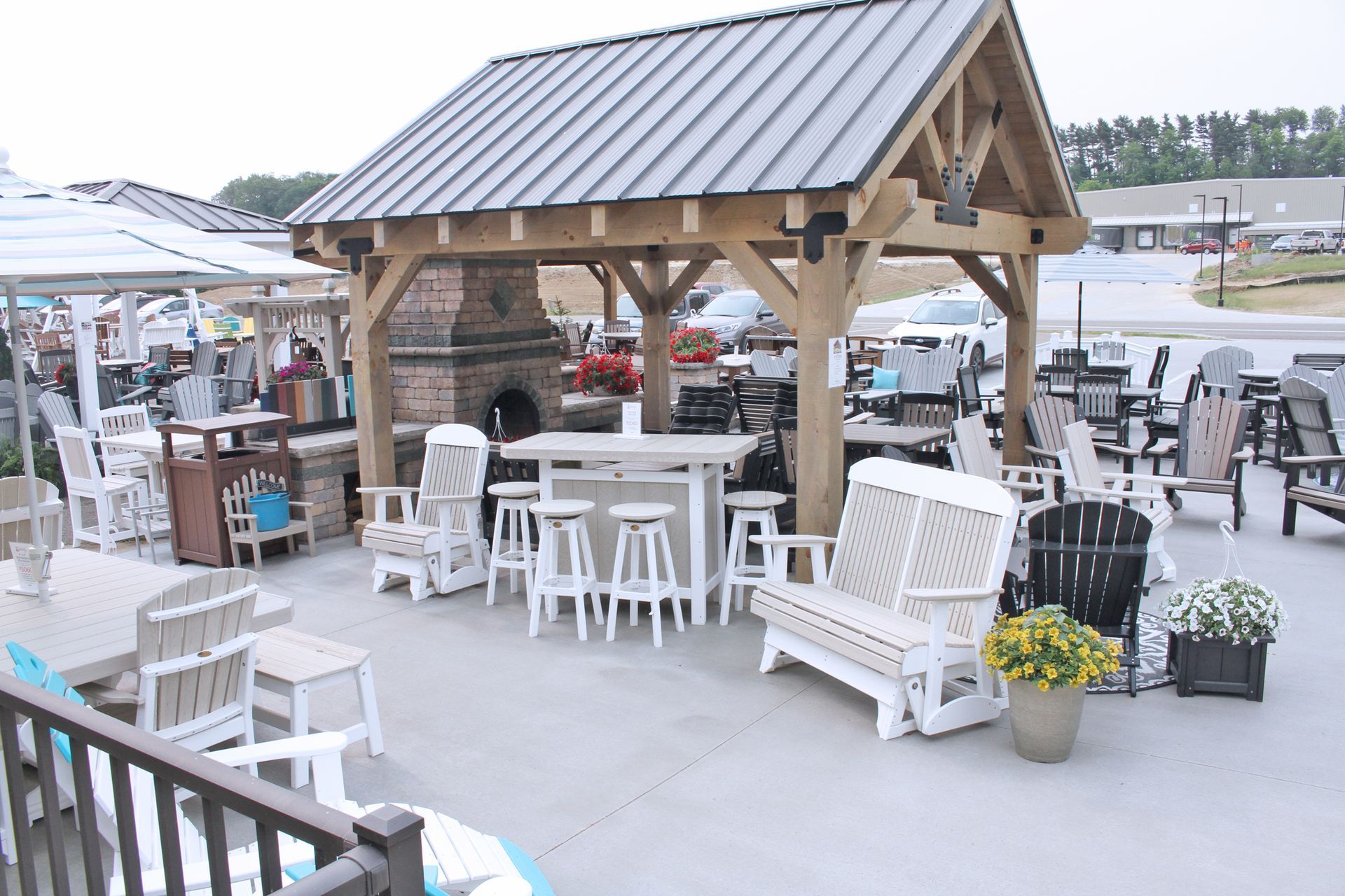Outdoor furniture display with wooden gazebo, tables, chairs, and benches.