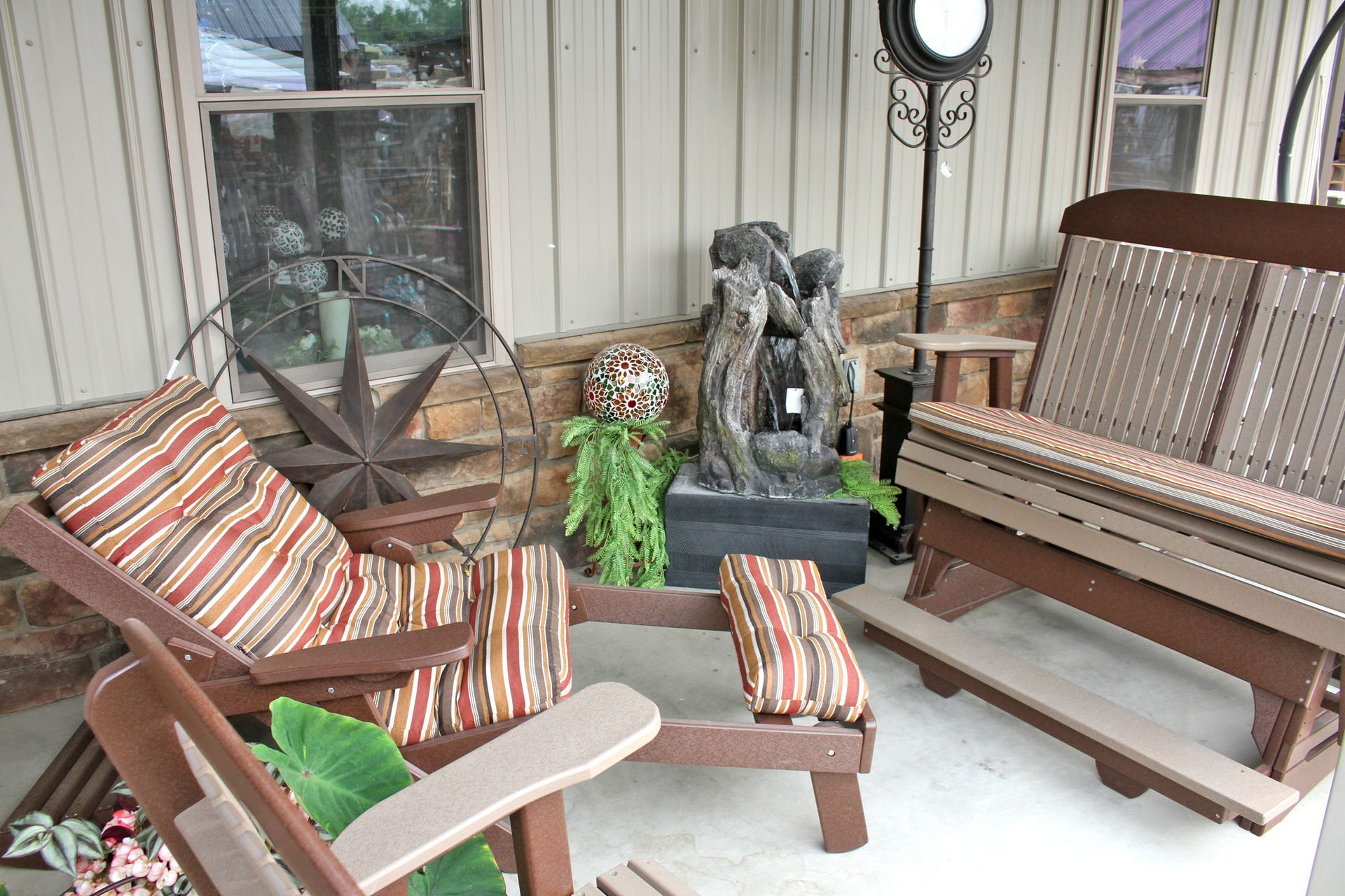 Outdoor patio with Adirondack chairs and a bench; water fountain and star decor.