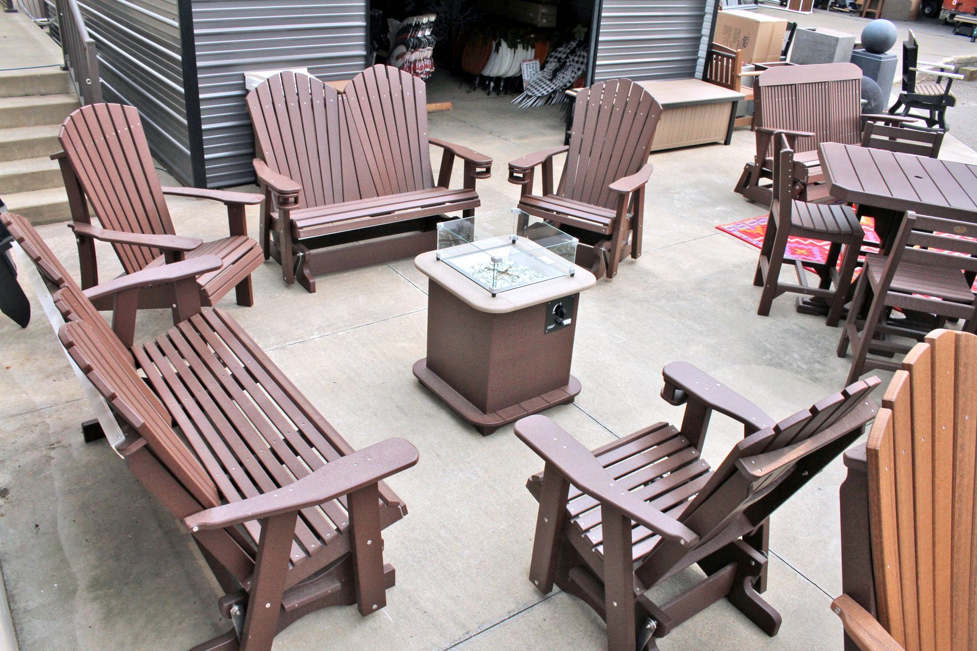 Outdoor patio furniture set, brown, arranged around a square fire pit.