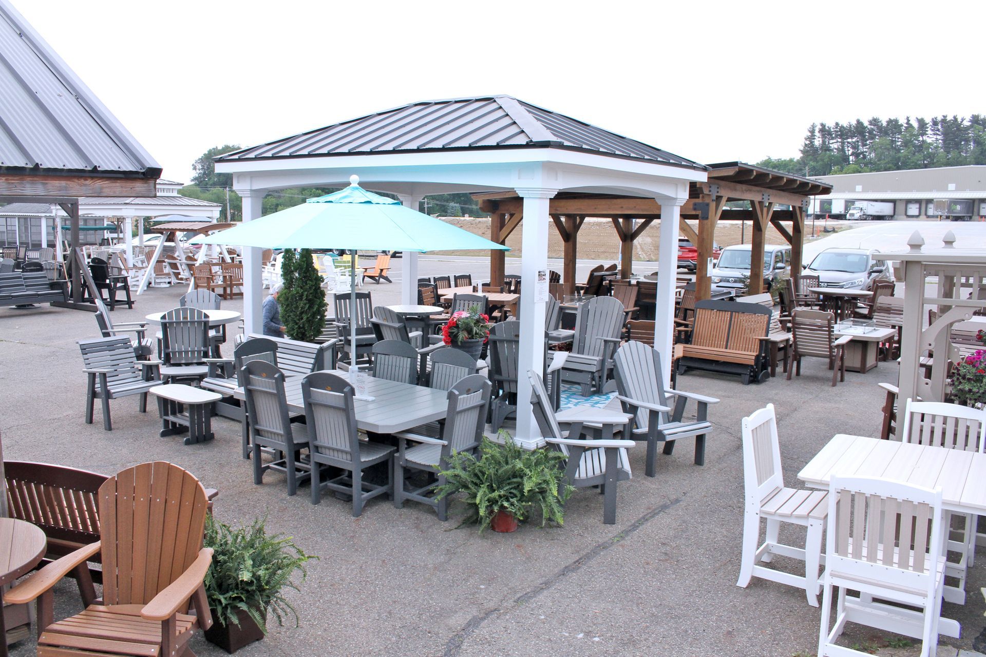 Outdoor furniture display with gazebos, tables, chairs, and umbrellas.