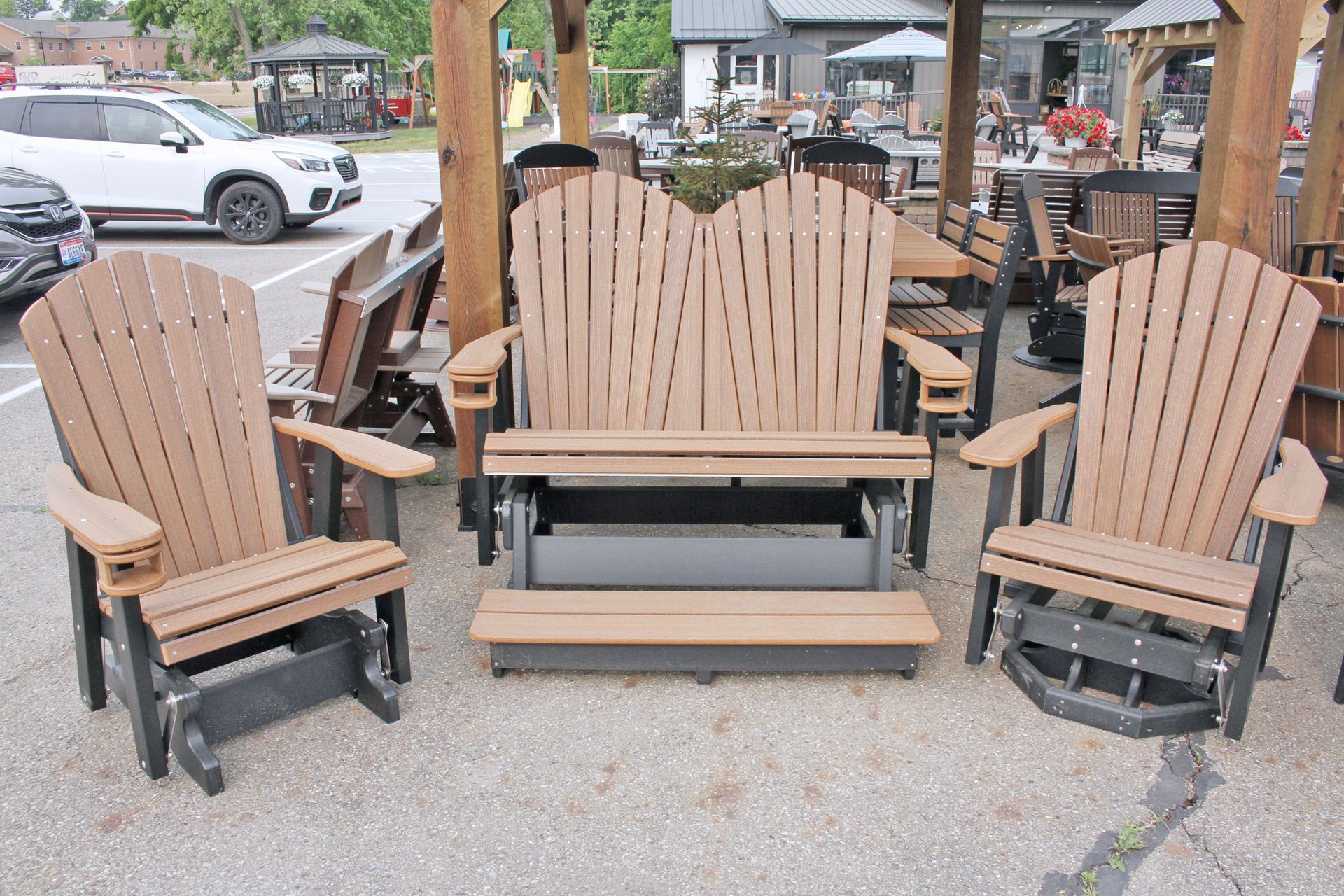 Outdoor furniture display: two brown and black Adirondack glider chairs, double glider bench.