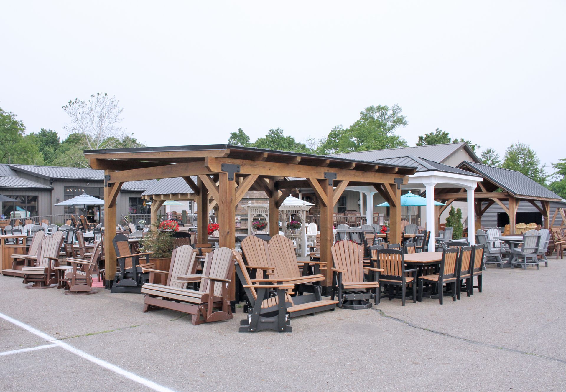 Outdoor furniture display under wooden pergolas in a store parking lot.