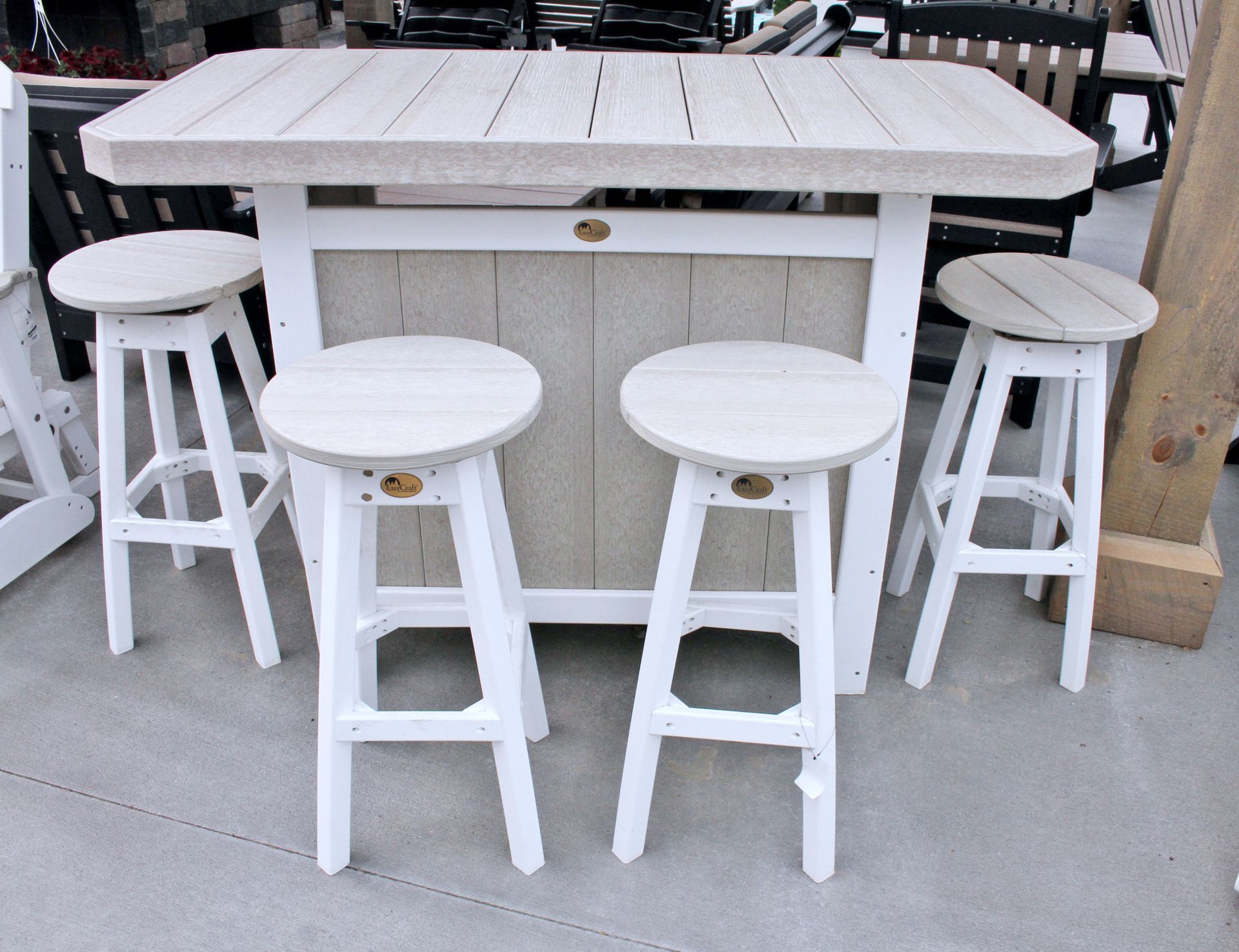 White outdoor bar set with four matching stools on a patio.