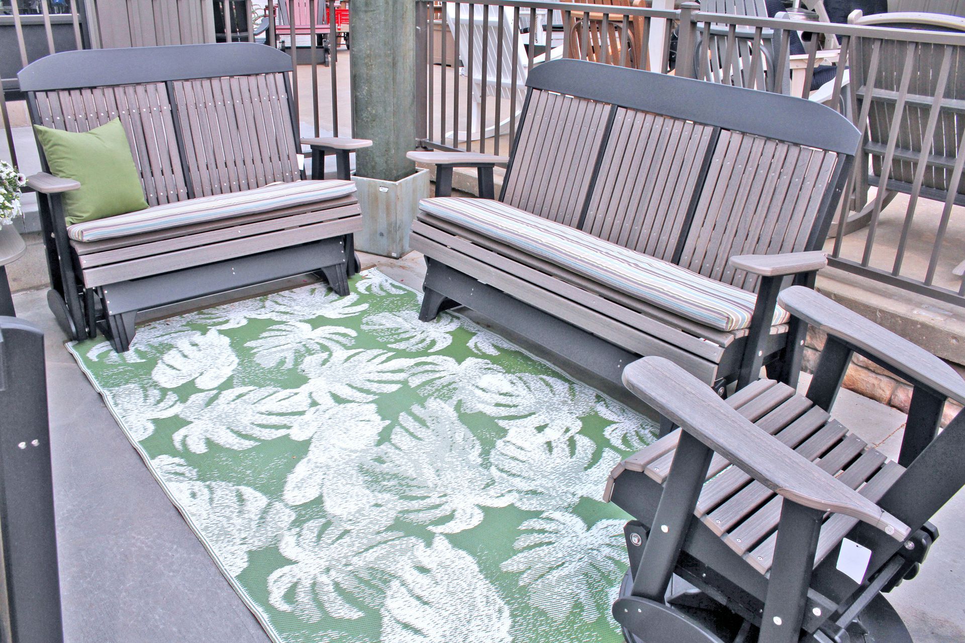 Outdoor seating set: two gliders, a loveseat, and a chair, on a green patterned rug.