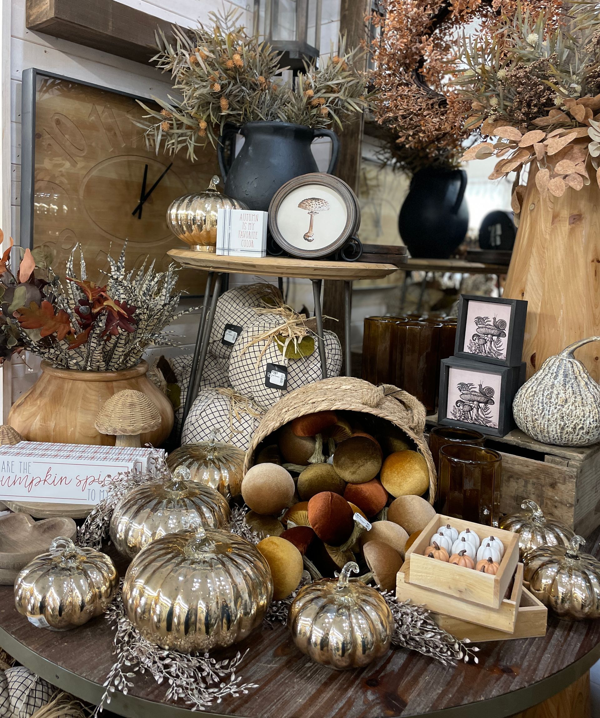 Fall decor display: gourds, pumpkins, dried florals, candles, and a clock.