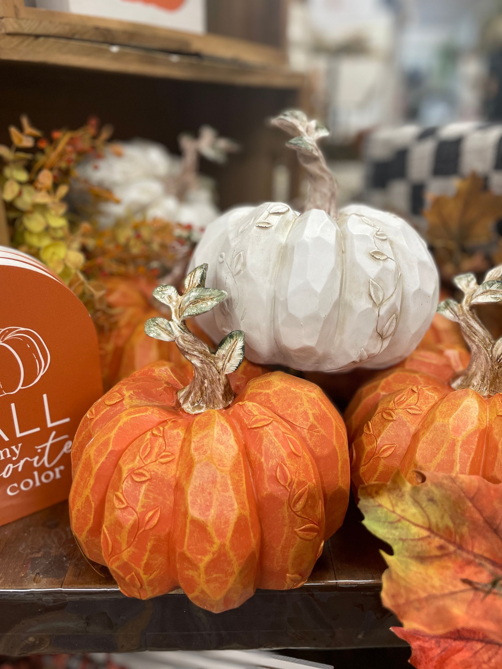 Close-up of decorative orange and white pumpkins with carved details and a fall-themed setting.