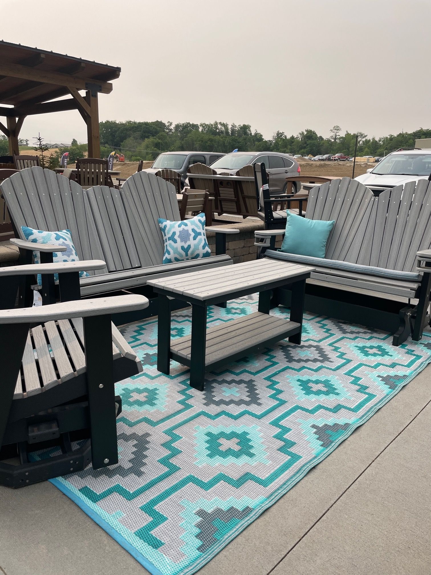 Gray and white outdoor glider set with turquoise rug and throw pillows.