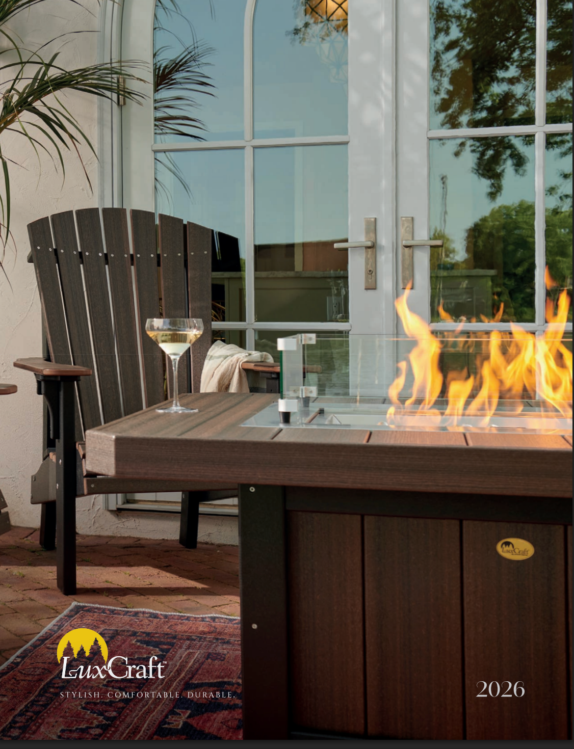Gray Adirondack-style glider chair with yellow pillow on patio next to a side table with a flower arrangement.