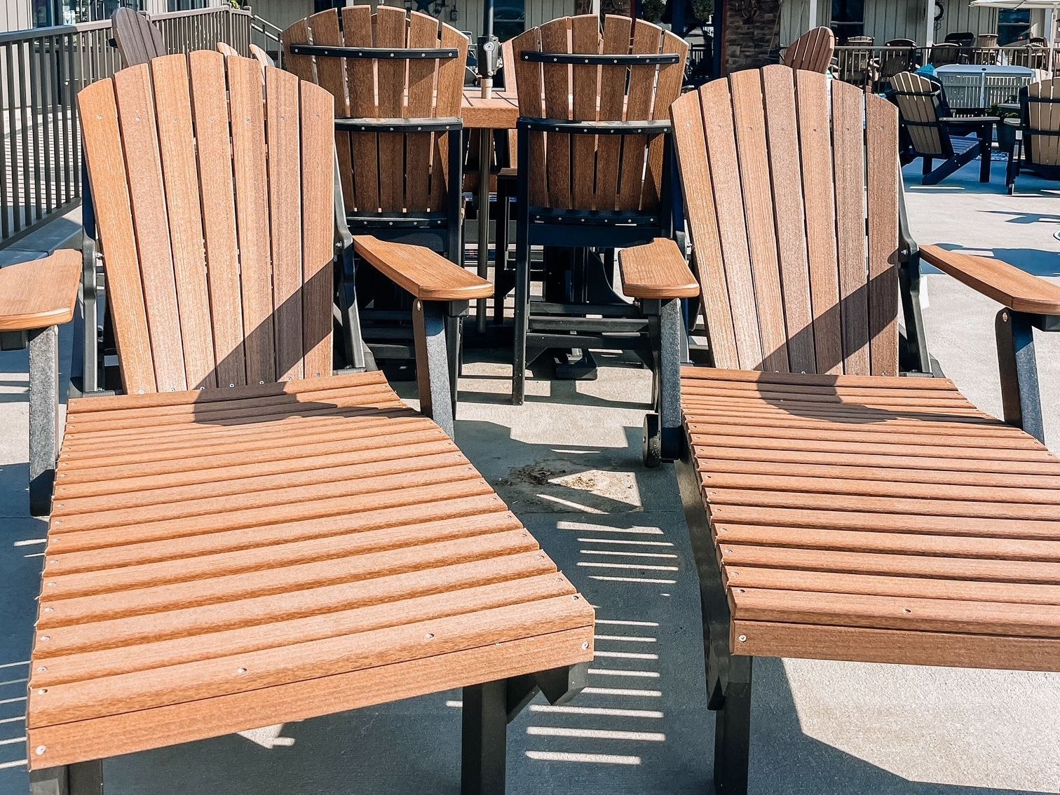 Two brown Adirondack chairs with armrests and slatted seats, outdoor patio.