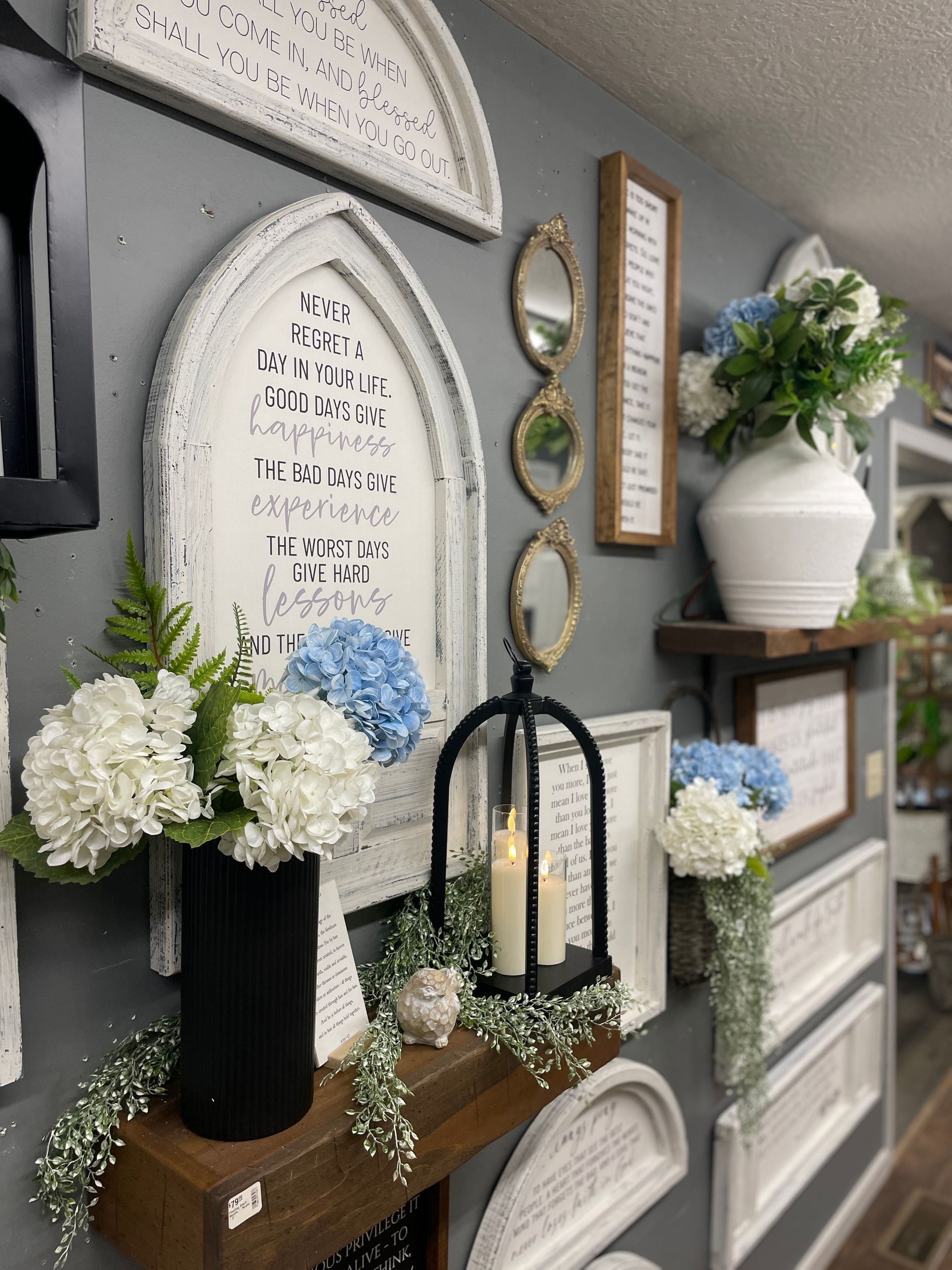 A display of decorative wall art and floral arrangements on a gray wall.