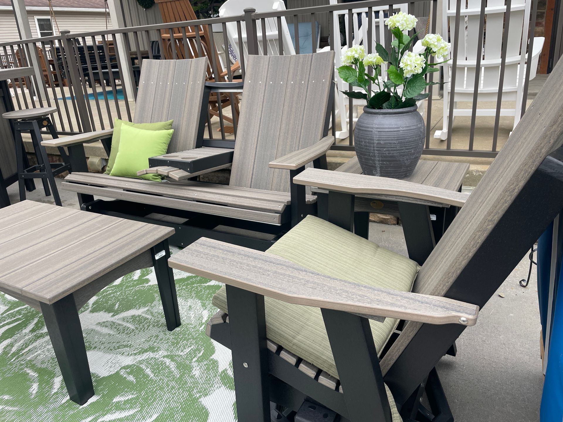 Patio furniture set: chairs, table, and bench, gray and black with green cushions.