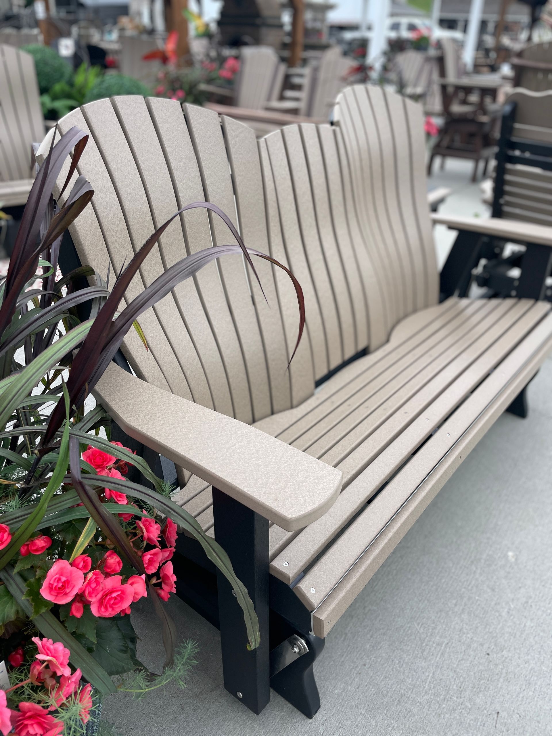 Tan and black outdoor double Adirondack bench with flowers.