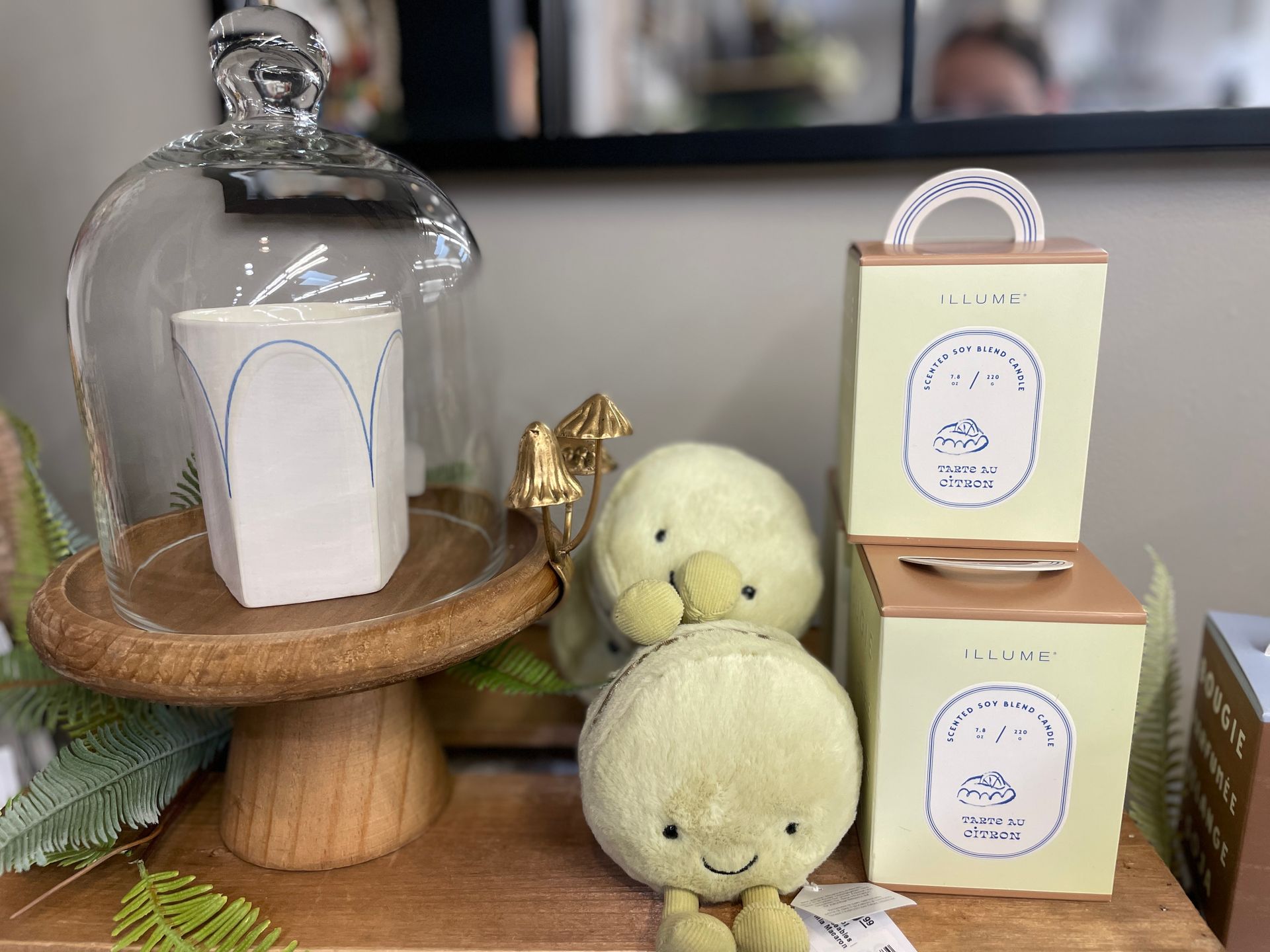 Display of decorative items, including a cloche-covered vase, stuffed plush toys, and boxed candles.
