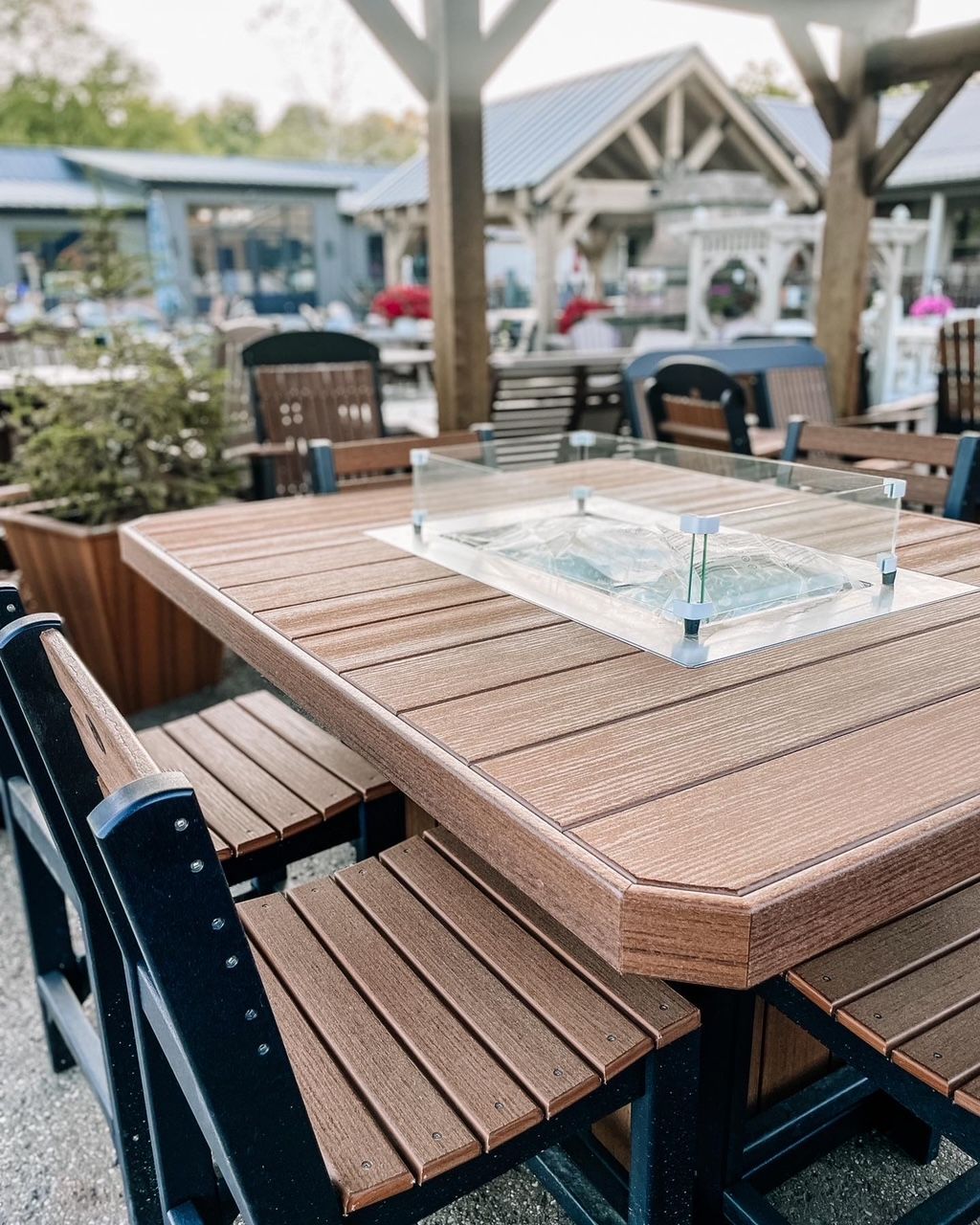 Outdoor patio furniture: brown table with built-in fire pit, chairs with black frames.
