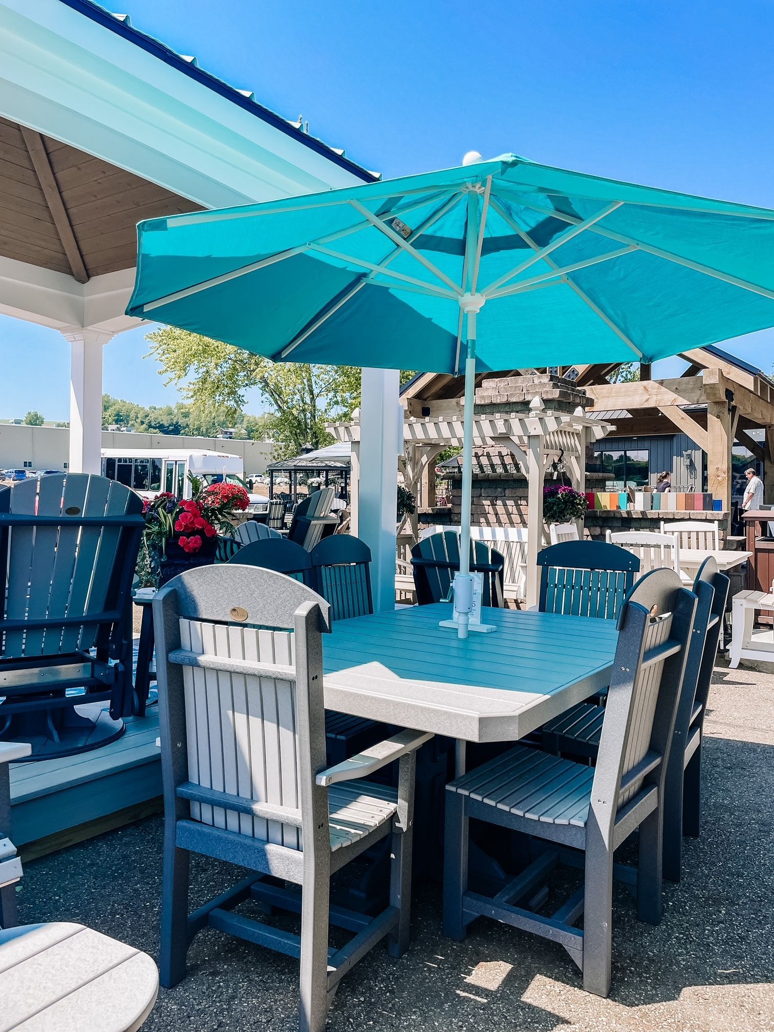 Outdoor dining set with teal umbrella. Gray table and chairs on a sunny day.