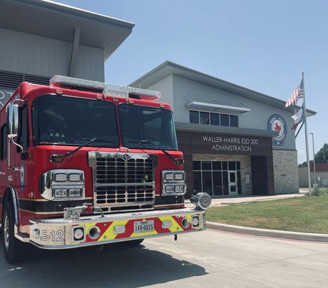 A red fire truck is parked in front of a fire station.
