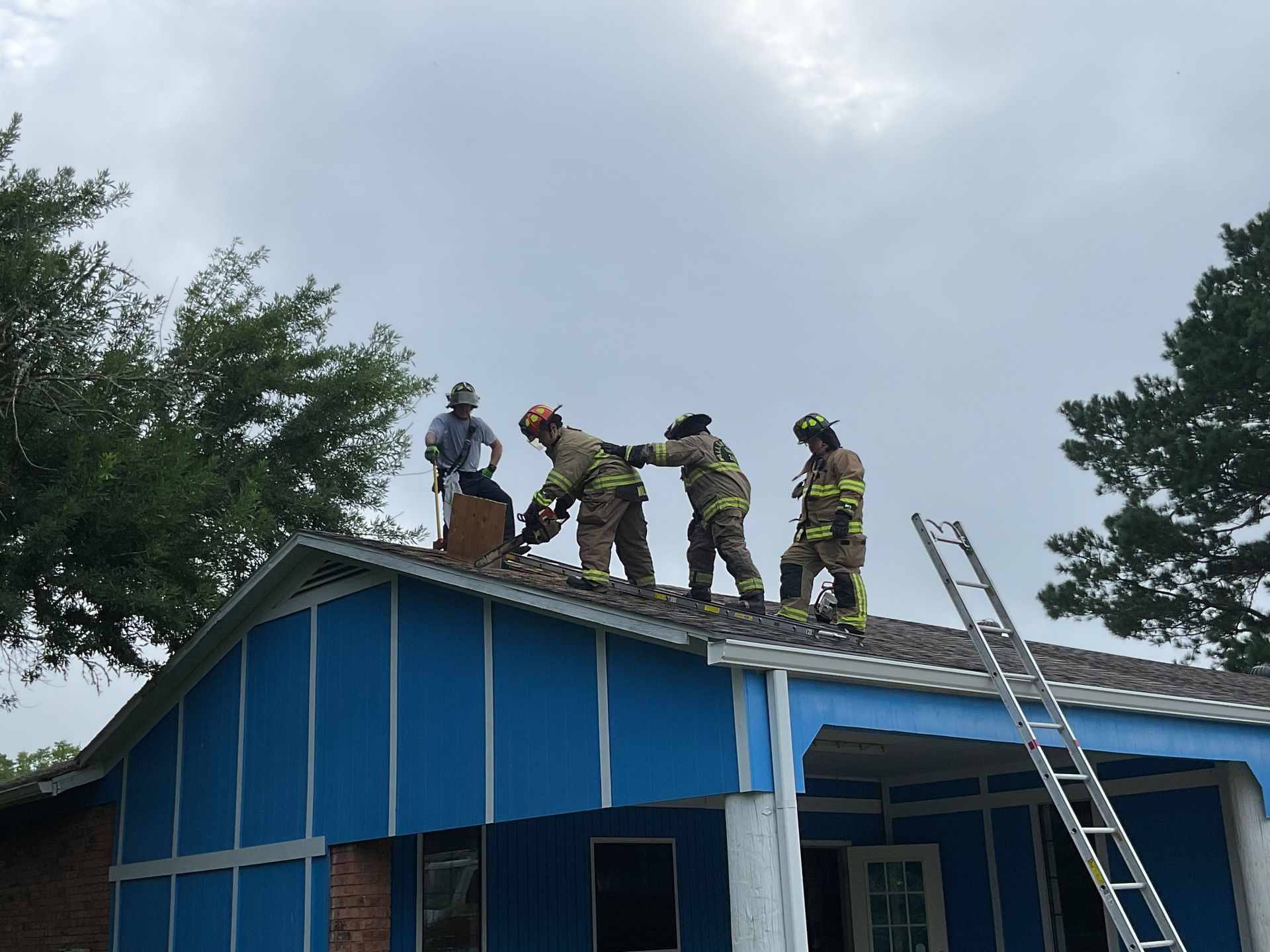 A group of firefighters are training on the roof of a house.
