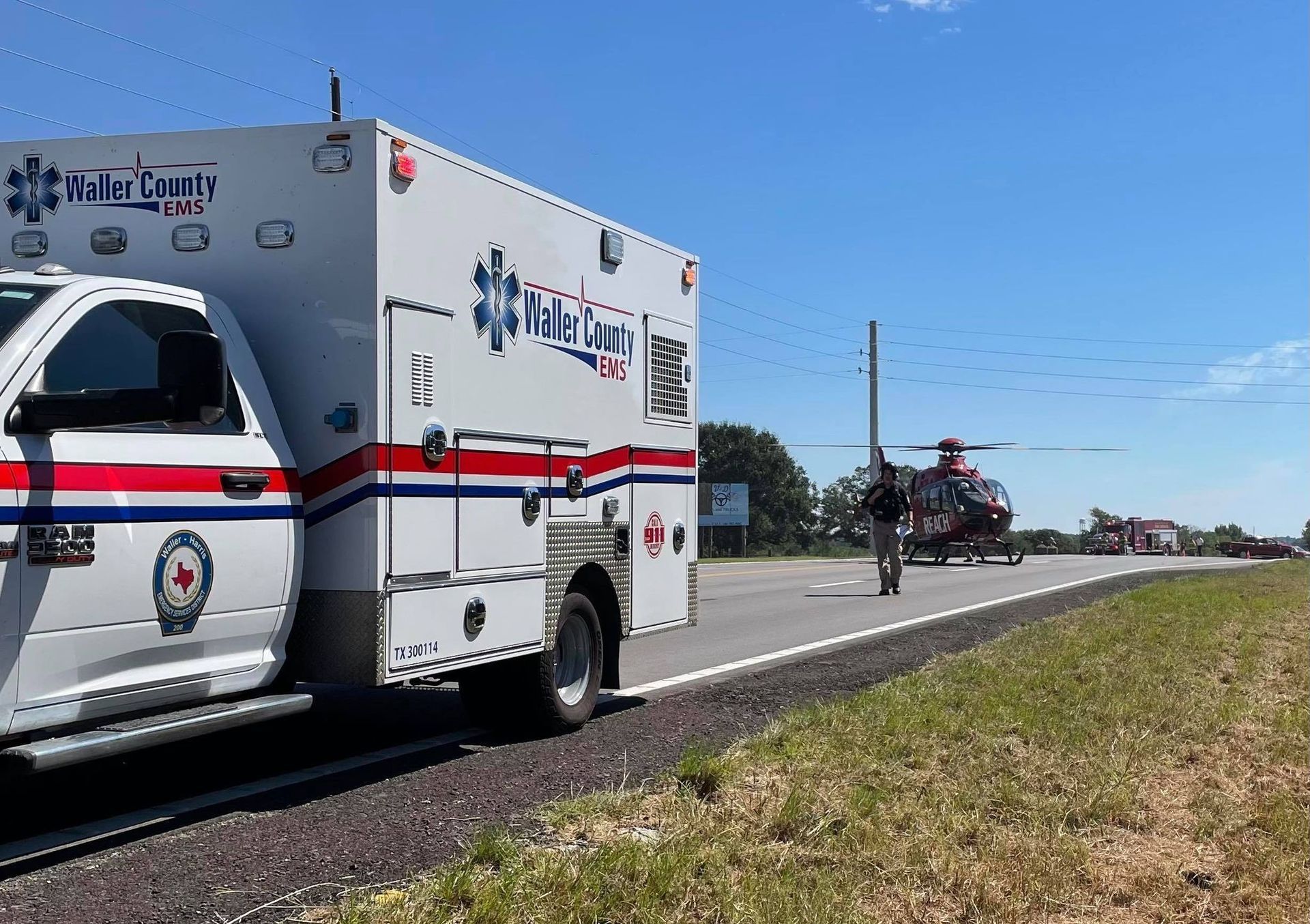 An ambulance is parked on the side of the road next to a helicopter.