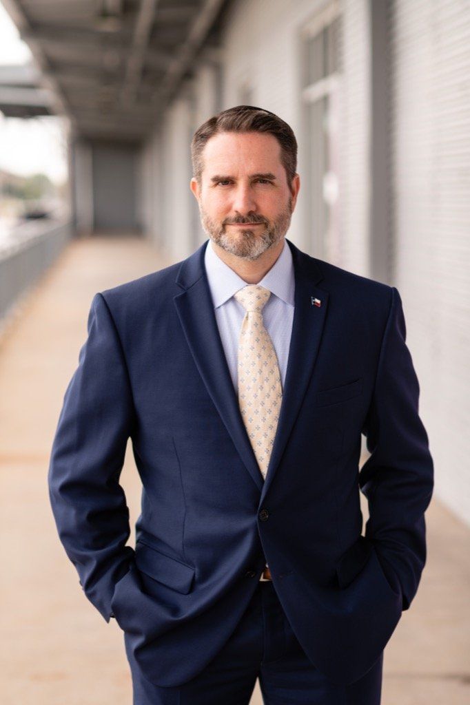 A man in a suit and tie is standing with his hands in his pockets.