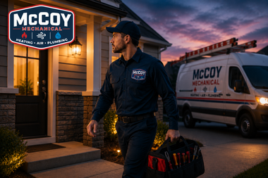 McCoy Mechanical technician carrying tools outside a home beside a service van at dusk