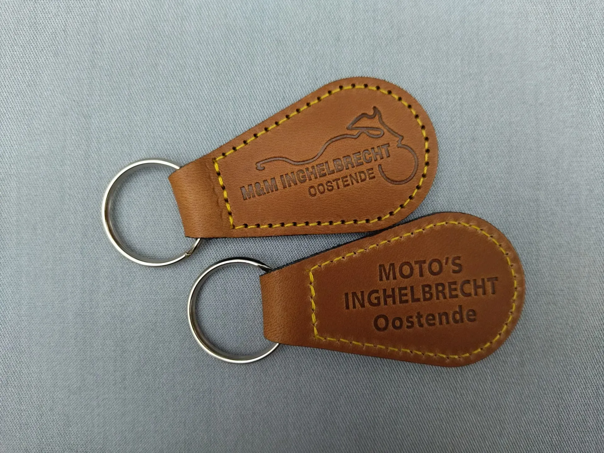 Twee bruine sleutelhangers met diepdruk van Inghelbrecht Oostendee