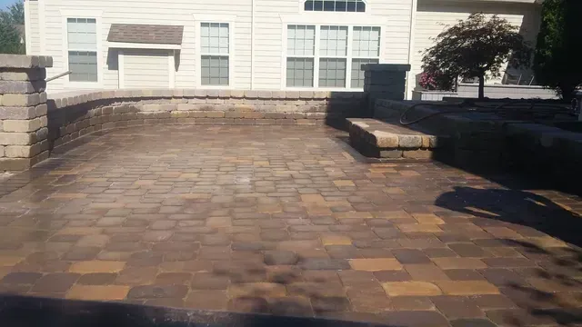 A brick patio with a bench in front of a house.