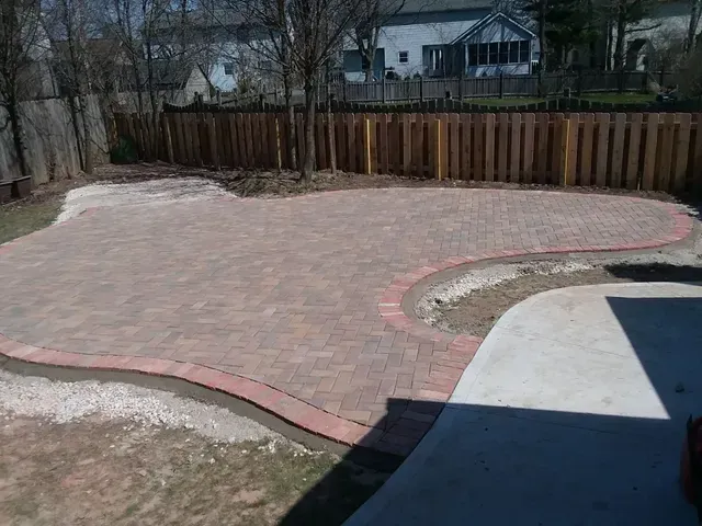 A brick patio with a wooden fence in the background.