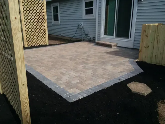 A patio with a wooden fence in front of a house.