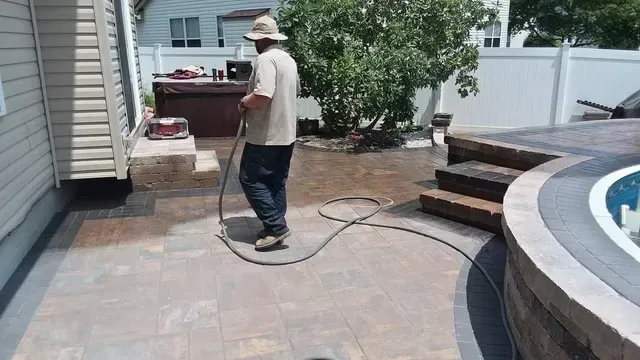 A man is cleaning a patio with a hose.