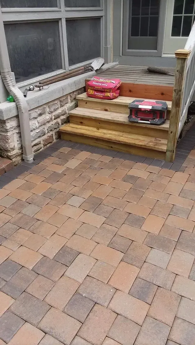A wooden staircase is sitting on top of a brick patio.