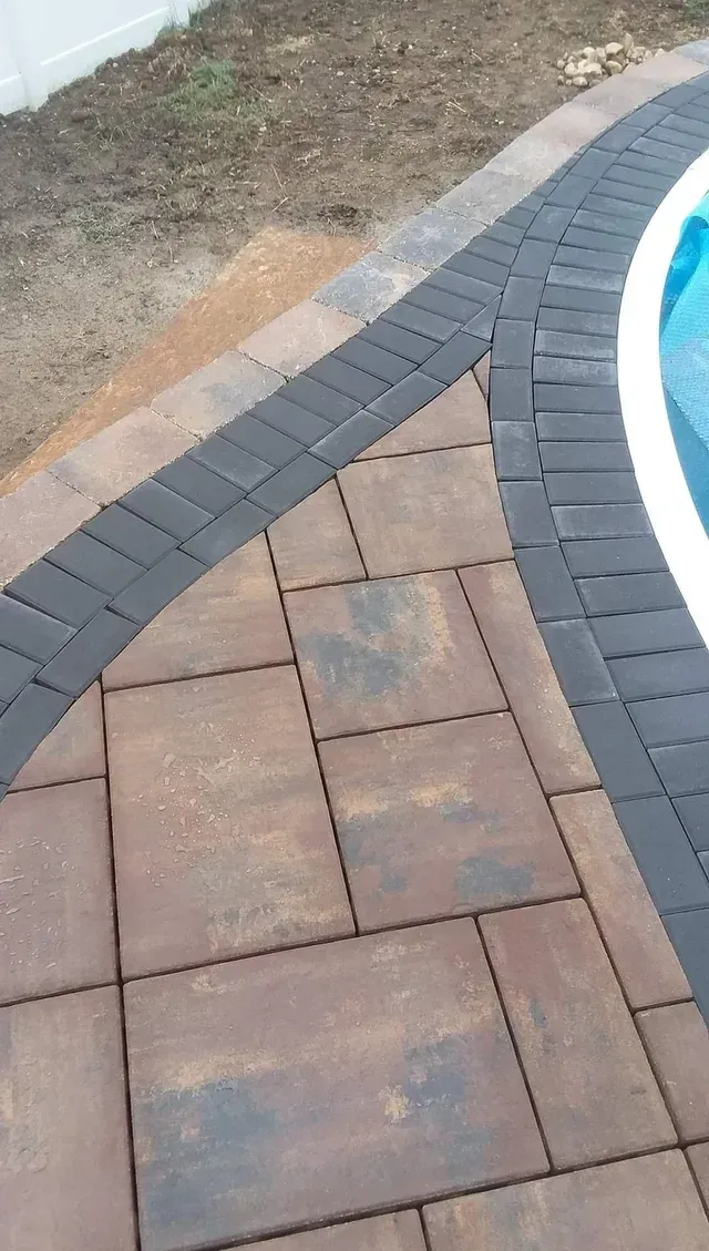 A brick walkway leading to a swimming pool.