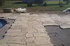 A patio is being built next to a pool.
