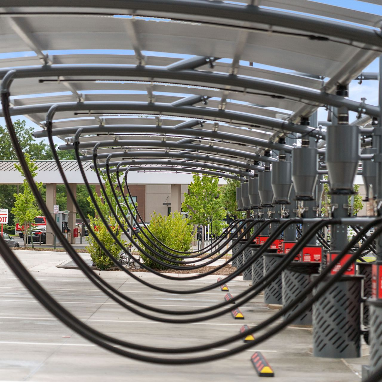 Row of car wash vacuum stations with overhead pipes and coverings.