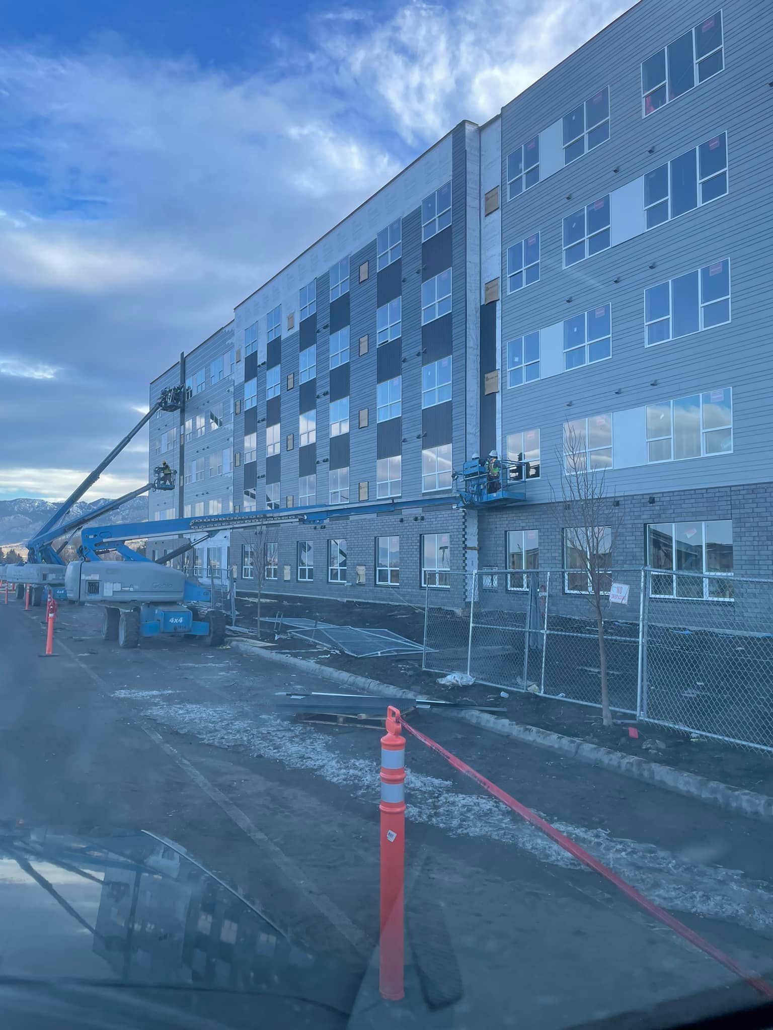 Building construction with multiple stories and blue crane, under a cloudy sky.