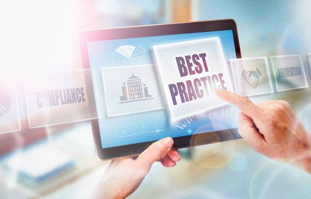 Hands tapping tablet with “Best Practice” on screen, blue and white corporate interface