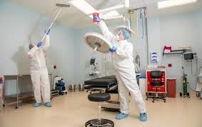 Two people are cleaning an operating room in a hospital.