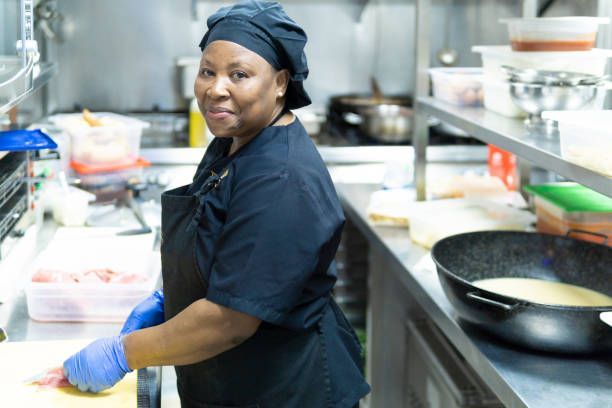 A woman is standing in a kitchen preparing food.