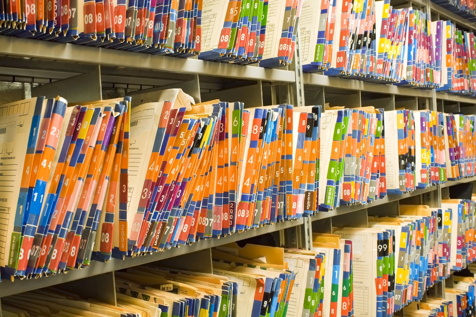 Rows of file folders in a storage system, with colorful tabs and labels.